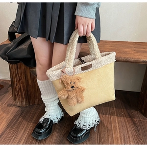 Detail of suede tote bag with plush sherpa trim and cute brown teddy bear pendant