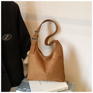 Close-up of brown suede hobo bag featuring adjustable silver buckle strap and outer pocket