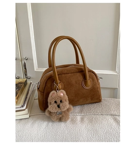 Brown suede handbag detail with smooth leather handles and cute plush puppy charm