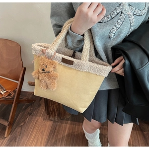 Detail of fuzzy cream fleece tote bag featuring a cute brown teddy bear charm