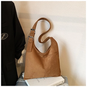 Detail of suede bucket bag featuring wide shoulder strap and double metal adjustment buckles