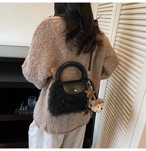 Detalle de bolso de mano negro de peluche con adornos de cuero y colgante de oso
