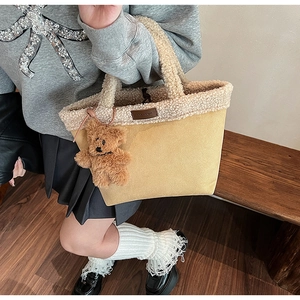 Detail of yellow faux suede bucket bag with plush white trim and a cute teddy bear charm
