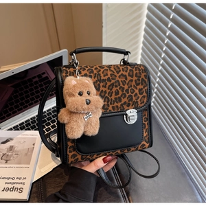 Détail du sac à main léopard et cuir noir avec un charmant pendentif chien en peluche