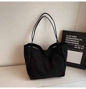 Détail de la texture et des anses du sac cabas en velours côtelé noir poli