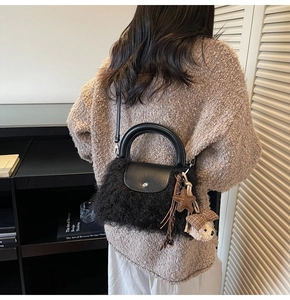 Detalle de bolso de mano de piel sintética negra con oso de peluche y correa de cuero