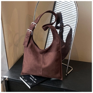 Detail of a brown suede hobo bag featuring an adjustable wide strap and silver metal buckles