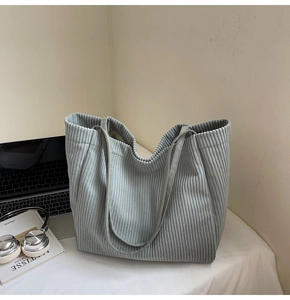 Détail du sac cabas en velours côtelé montrant la texture et des accessoires de bureau