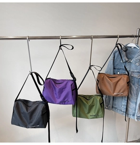 Detail view of four checkered canvas crossbody bags in black, purple, green, and brown