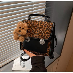 Détail d'un sac à main léopard avec boucles métalliques et un charme d'ours peluche