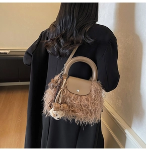 Vista detallada del bolso de peluche marrón con asa de cuero y colgantes en un modelo