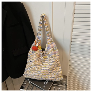 Close-up of rainbow knit tote bag with colorful woven texture and red fruit pendant charm