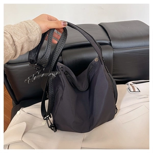 Detailed macro view of black nylon bag with multiple zipper pockets and wide shoulder strap