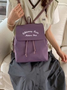 Fashionable purple drawstring backpack with white embroidery shown from the back on a model