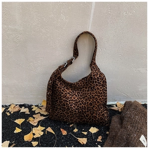 Close-up of leopard print hobo bag with ginkgo leaf rivets on a natural textured background