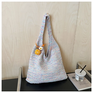 Detail of colorful rainbow hand-woven tote bag with cute crochet orange pendant charm