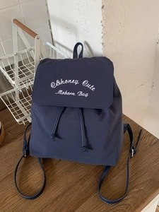 Dark blue nylon backpack with white embroidery and adjustable straps for daily use