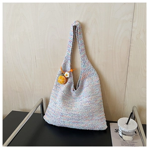 Detail of colorful knitted tote bag with rainbow textures and orange charm accessory