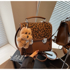 Detail of leopard print backpack with silver clasps and brown plush bear keychain