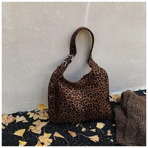 Detail of leopard print hobo bag with adjustable metal buckle on autumn leaves