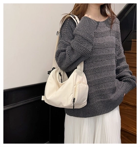 Detail view of off-white convertible shoulder bag with pleated nylon and wide fabric strap
