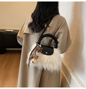 Detalle de bolso de piel sintética blanca con asa de cuero negro y colgante de oso