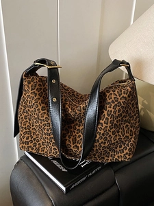 Stylish large leopard print tote bag with black leather straps on a modern leather stool