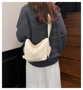 Detail of off-white waterproof nylon crossbody bag with wide strap and side zipper pocket