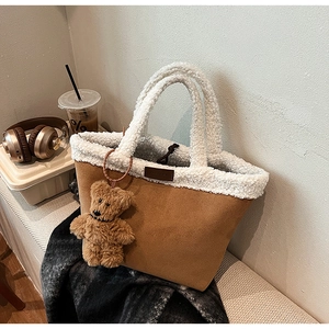 Detail of fuzzy faux shearling trim and brown suede tote bag with a cute bear charm