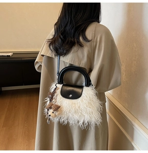 Detalle del bolso de piel sintética blanca con asa de cuero negro y colgante de osito
