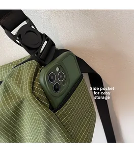 Detail view of the side zipper pocket on a green checkered crossbody bag with a phone