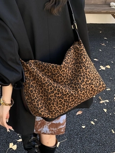Stylish oversized leopard print tote bag with black leather straps in a street scene