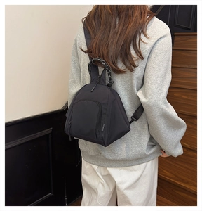 Close-up of model wearing black nylon outdoor mini backpack with durable zipper pocket