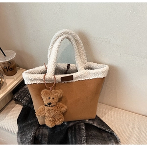 Detail of winter tote bag with brown suede texture and white sherpa handles