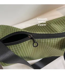 Detail of smooth metal zipper and green plaid fabric on this crossbody bag