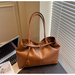 Detailed macro view of the brown leather tote bag texture with elegant metal buckle detail