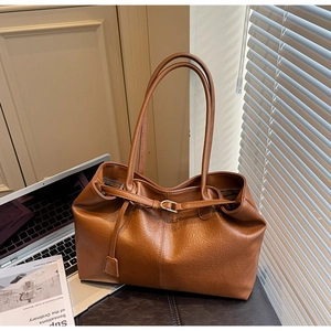 Detailed view of caramel brown lychee leather tote bag with a small hanging purse