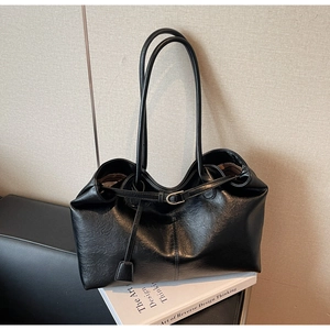 Macro detail of black leather tote bag featuring natural grain texture and strap buckle