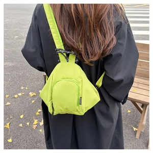 Bright green lightweight waterproof mini backpack shown as a crossbody on a model outdoors