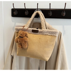 Close-up of beige suede tote bag with white faux shearling trim and cute bear charm