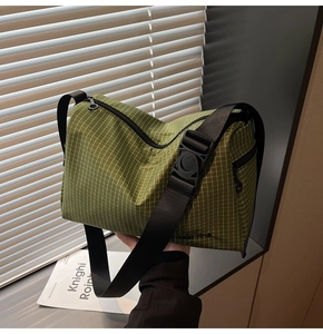 Close-up of green checkered canvas crossbody bag with adjustable black strap and zipper