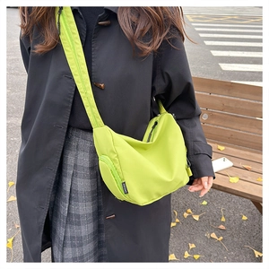 Neon green waterproof nylon backpack worn as a crossbody bag in an urban street setting