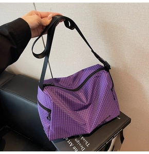 Detail of purple and white checkered canvas bag with adjustable black shoulder strap