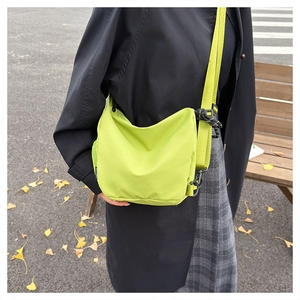 Detail of water-resistant green nylon crossbody bag with strap and black hook buckle