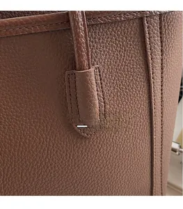 Detailed close-up of stitching and pebble grain leather on a brown tote handbag