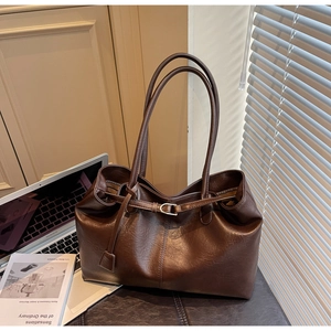 Detail of vintage brown leather tote bag with metallic buckle in a professional workspace