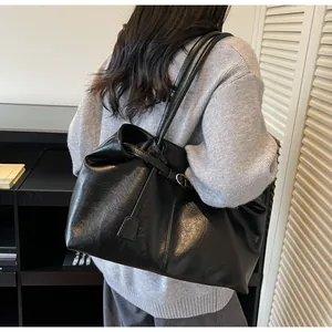 Detail view of the black glossy leather shoulder bag with natural wrinkled texture