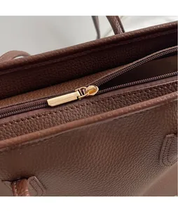 Macro shot of golden metal zipper and brown lychee grain leather texture on tote bag