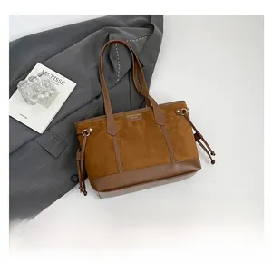Flat lay of a vintage brown leather tote bag with drawstring detail on a grey suit jacket