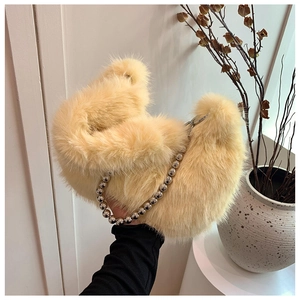 Detail of fluffy light yellow plush handbag featuring decorative silver bead handle